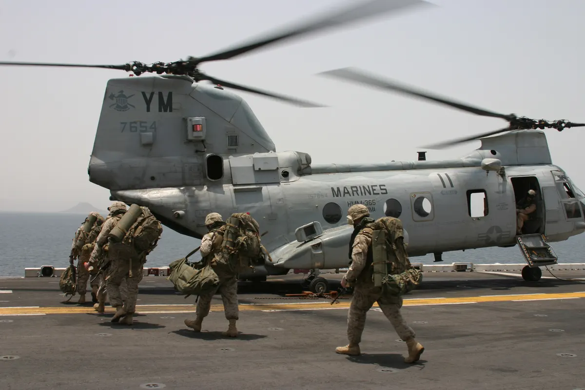 Denizci personeli, CH-46 Sea Knight'ın arka rampasından kargo yüklüyor